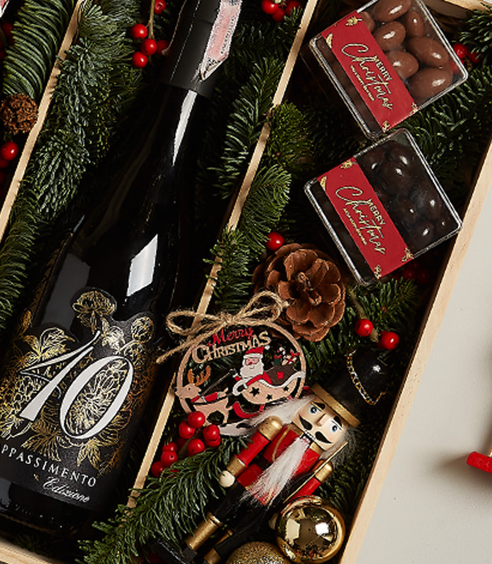 Elegant wine celebration box with Appassimento red wine, chocolate-covered nuts, and festive Christmas ornaments in wooden