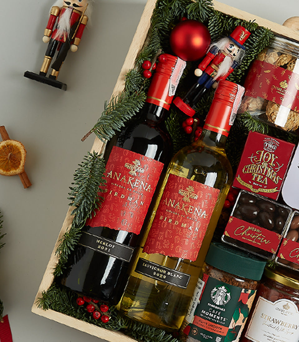 Premium wooden crate gift hamper with red and white wines, festive garland, gourmet treats, and holiday ornaments