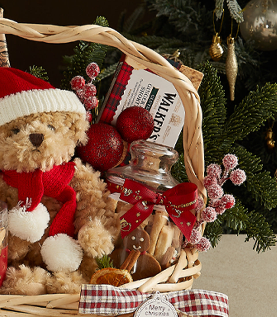 Festive Christmas gift basket with plush teddy bear in Santa hat, gourmet cookies, shortbread, and holiday ornaments