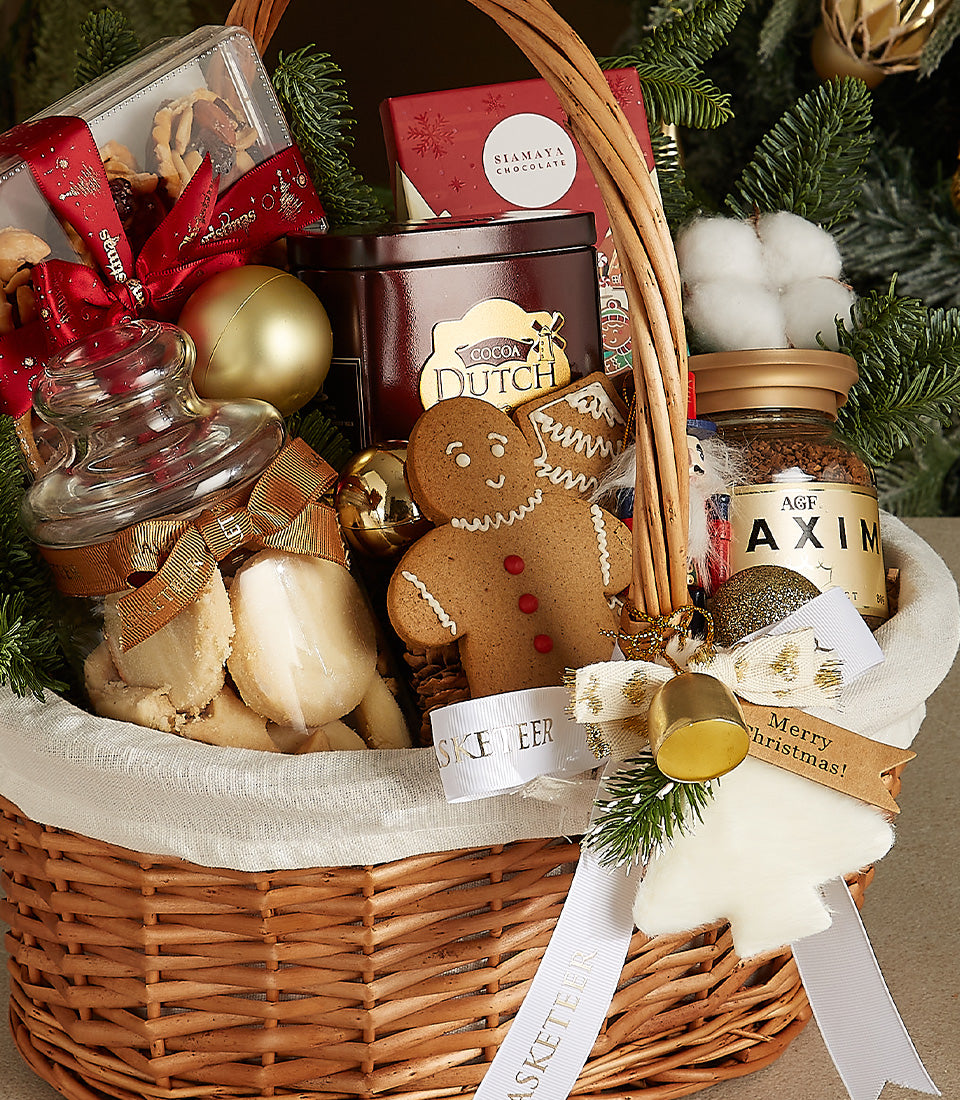Festive woven Christmas gift basket with gourmet chocolates, cookies, coffee, and gold ornaments