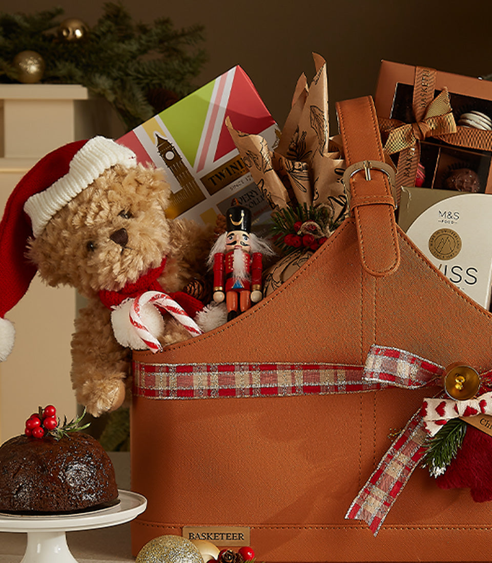 Festive leather holiday gift basket with teddy bear, nutcracker, tea, and Christmas pudding for classic British celebrations