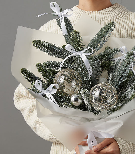Festive floral Christmas bouquet with frosted pine, silver ornaments, and white satin ribbon