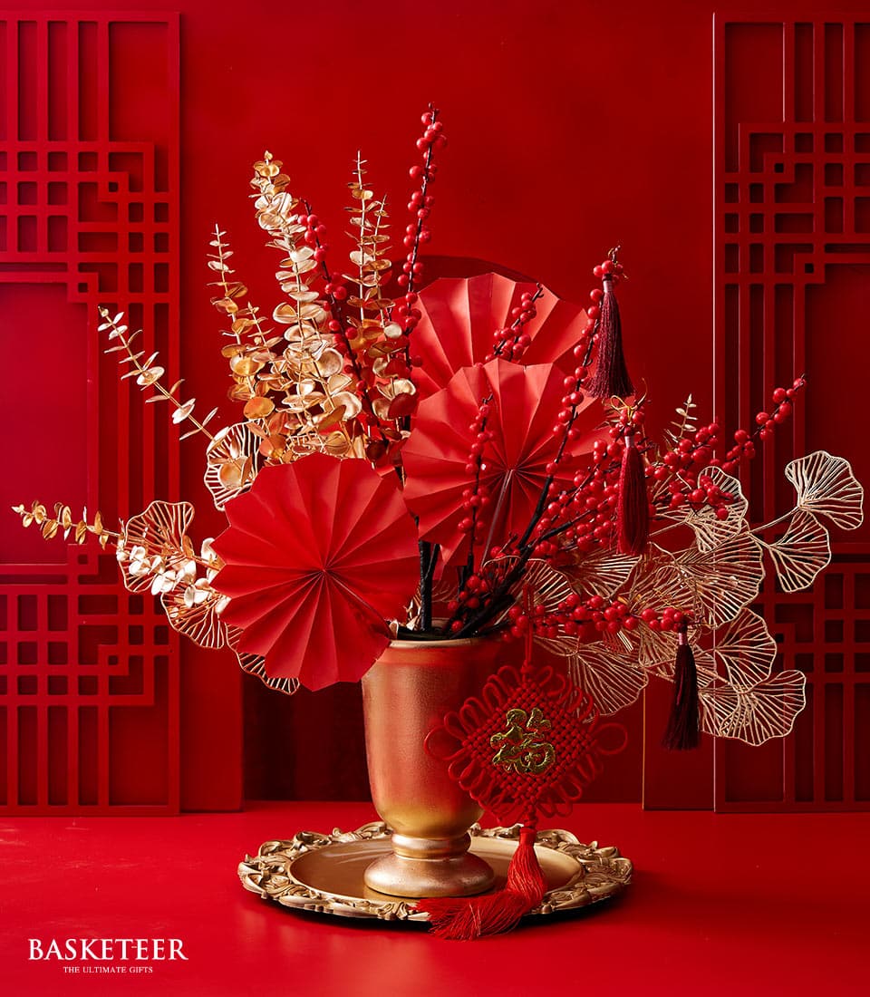 Lunar New Year floral arrangement with red branches and golden foliage in ornate gold vase