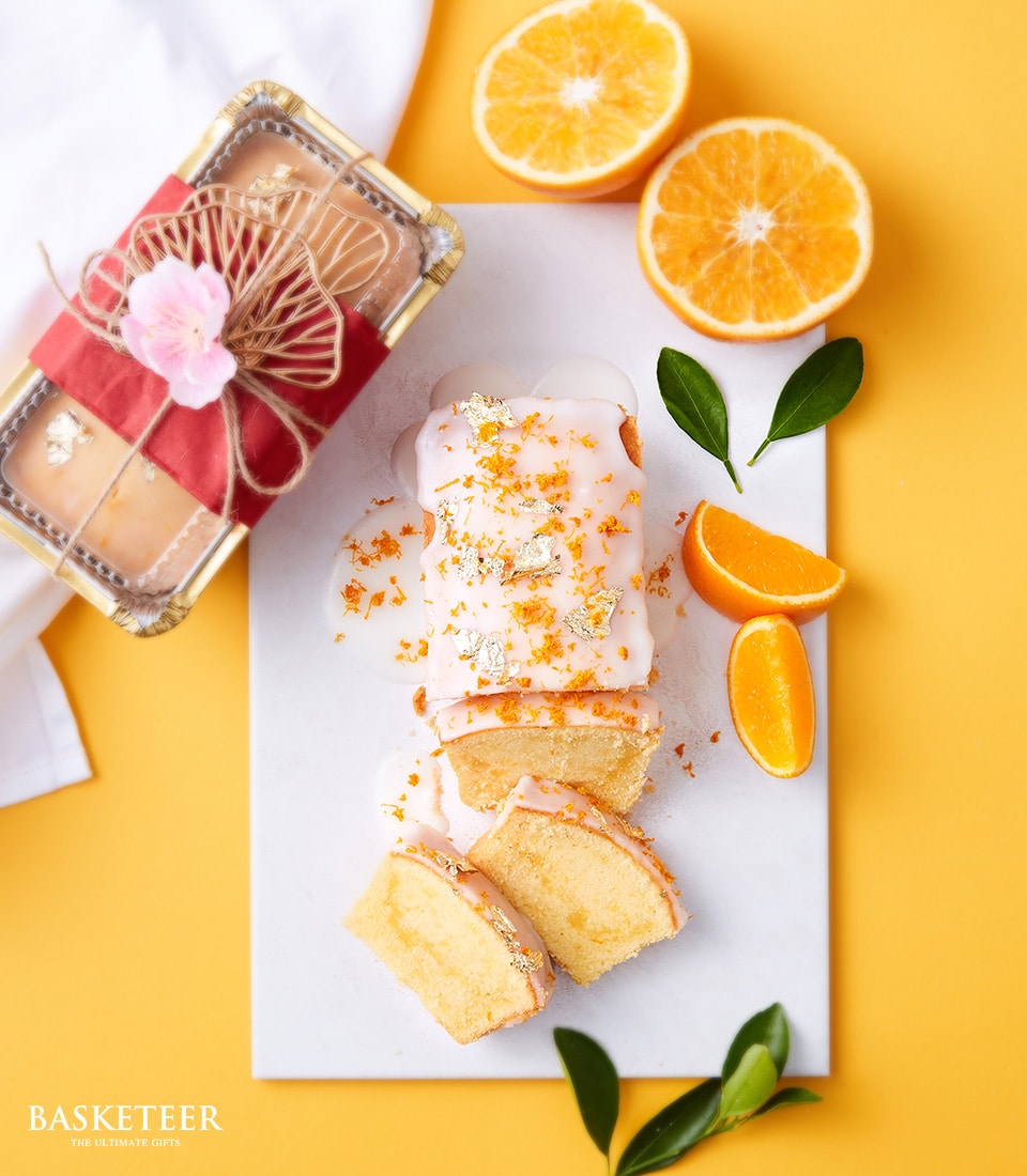 Charlotte Bakery mandarin zest pound cake with white icing, orange zest, and gold leaf for Chinese New Year gifting