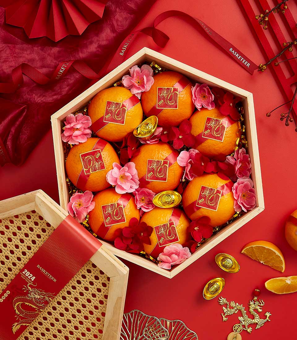 Mandarin Lunar New Year gift basket with fresh oranges, golden dragon charms, and red silk ribbons on festive red background