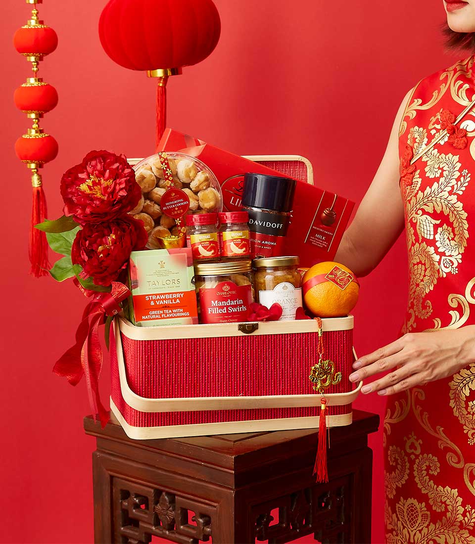 Festive red gift basket with Chinese New Year snacks, butter cookies, tea, and chocolates, adorned with peonies and gold
