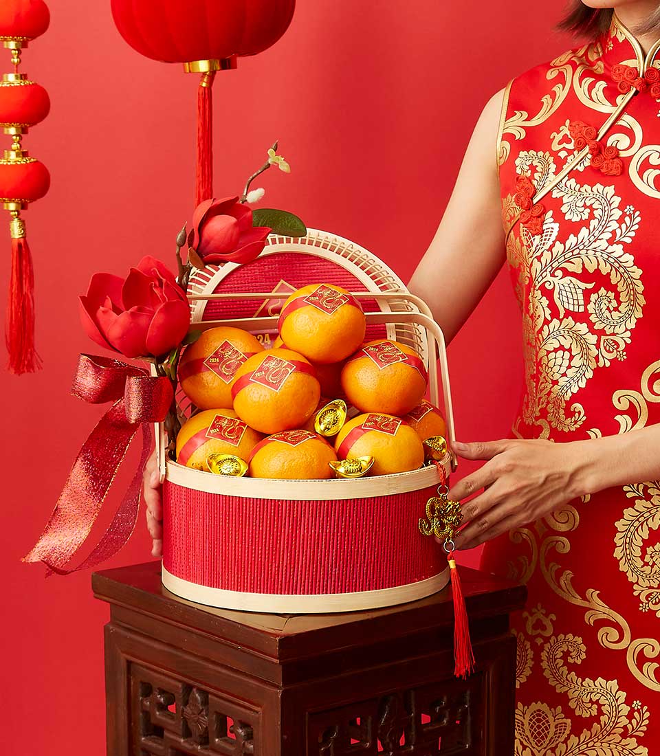 Festive red and gold Chinese New Year gift basket with fresh oranges, gold ingots, and lucky charms