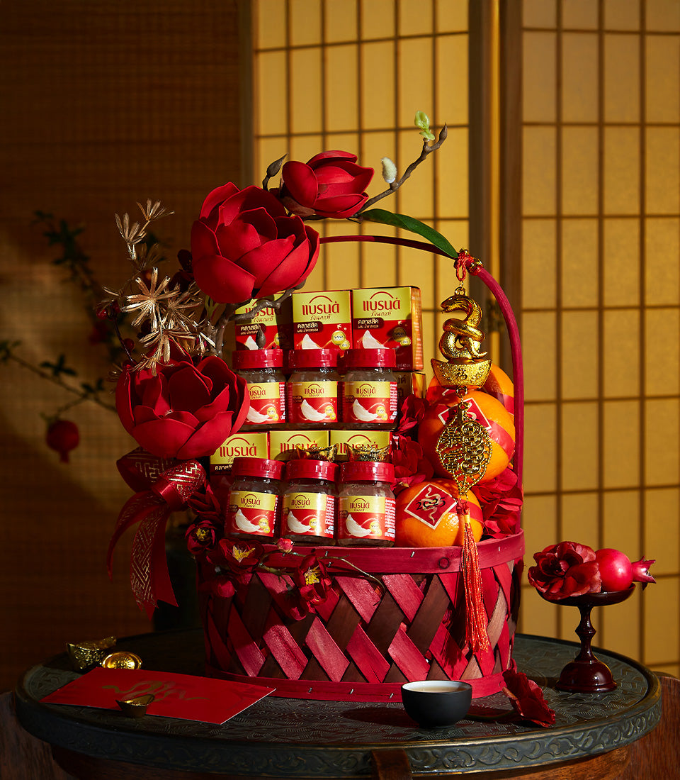 Deep red woven gift basket with premium bird's nest jars, golden dragon ornaments, and fresh oranges for Chinese New Year