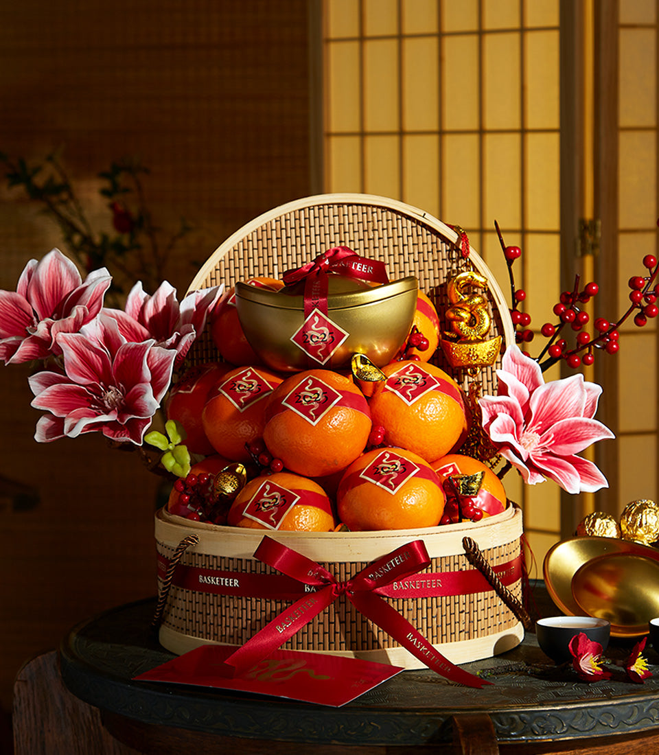 Golden prosperity gift basket with mandarins, dragon ornaments, and red accents for Lunar New Year