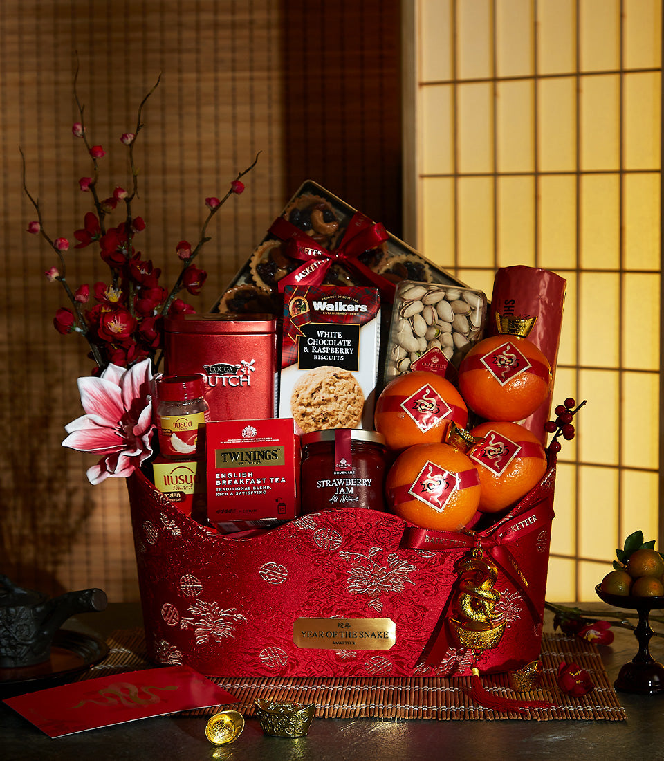 Deluxe red and gold Chinese New Year gift basket with gourmet treats, fresh oranges, and festive decorations