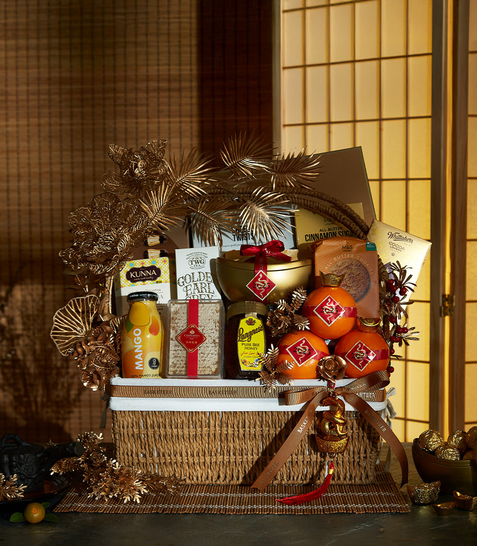 Woven rattan luxury hamper with gourmet treats, golden crown oranges, and festive dragon charm for Chinese New Year