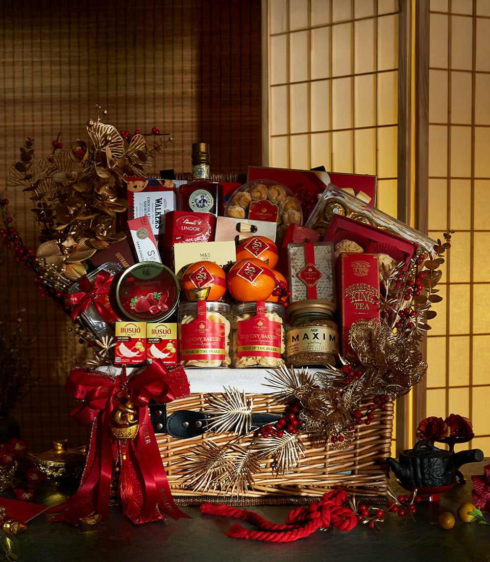 Luxury wicker gift hamper with red satin bow, gold foliage, oranges, and gourmet treats for Lunar New Year