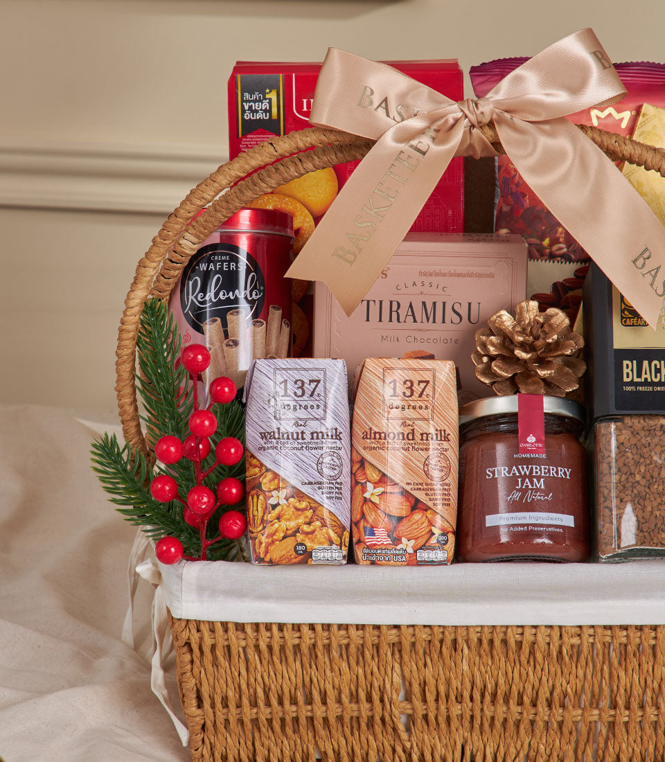 Woven wicker gift basket with coffee, premium biscuits, plant-based milk, and jam tied with gold satin ribbon for New Year