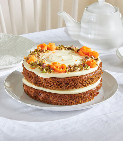 Frosted carrot sponge cake with cream cheese icing, candied carrot curls, and pistachios