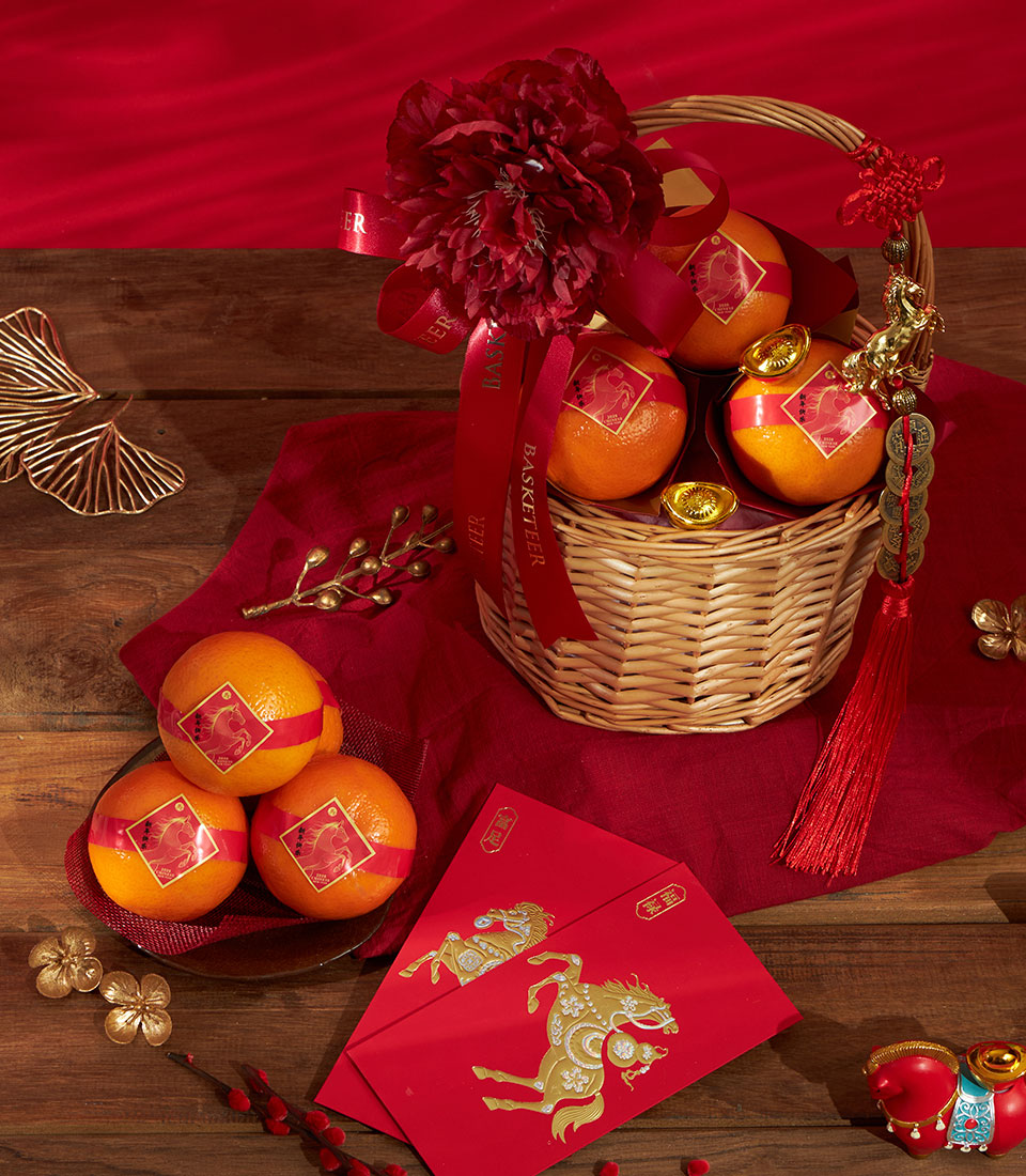 Woven wicker basket with fresh mandarin oranges, gold ingots, and red festive ribbons for Chinese New Year