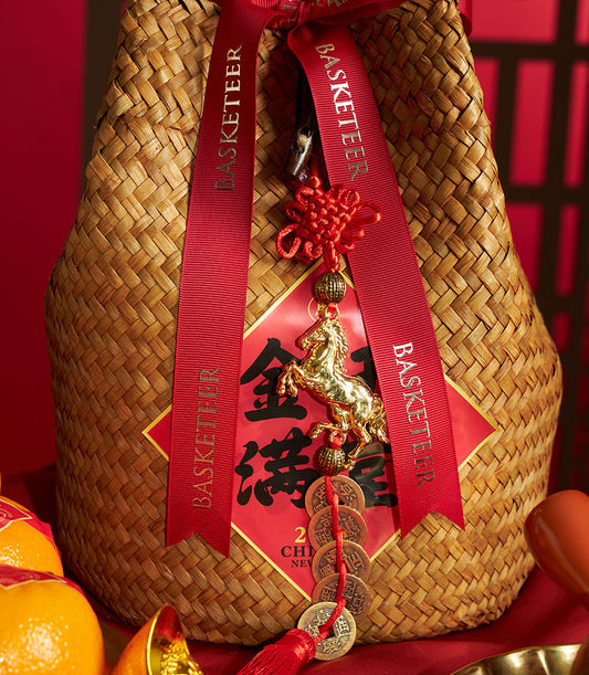 Woven straw gift basket with mandarin oranges, red ribbons, Chinese knot charm, and gold coins for Chinese New Year