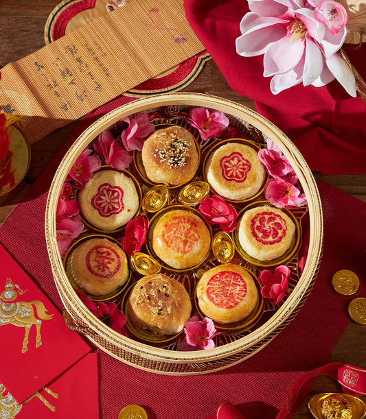 Assorted Chinese pastry gift basket with sesame and red-decorated mooncakes, golden ingots, and festive red accents for
