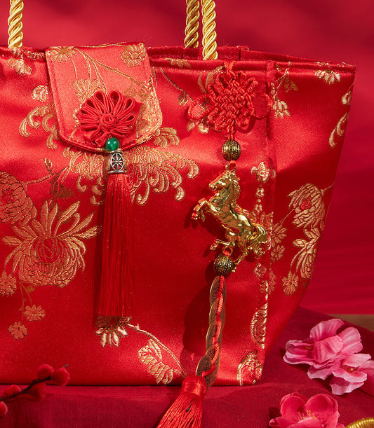 Red embroidered Chinese New Year gift bag with gold cord handles and lucky charm