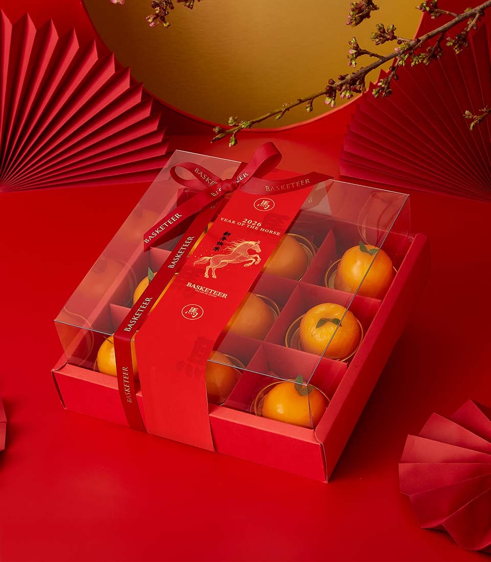 Festive red gift box with nine golden mandarin chiffon cakes for Chinese New Year, decorated with Year of the Horse ribbon