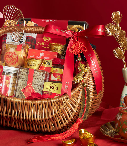 Premium Chinese New Year gourmet hamper with British bakery treats, wellness essentials, and gold lucky charms in red wicker