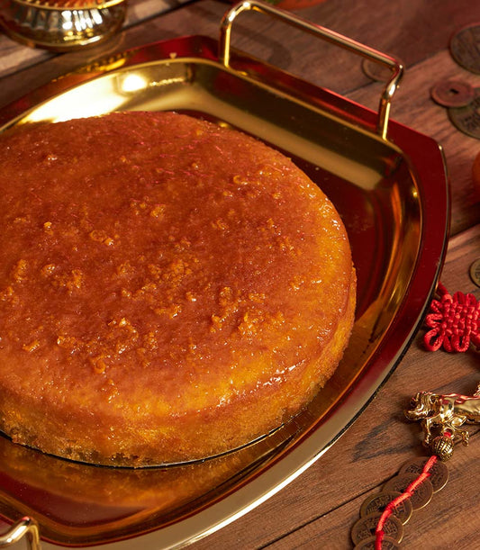 Golden mandarin sponge cake with glossy glaze on gold tray, Chinese New Year gift with auspicious décor