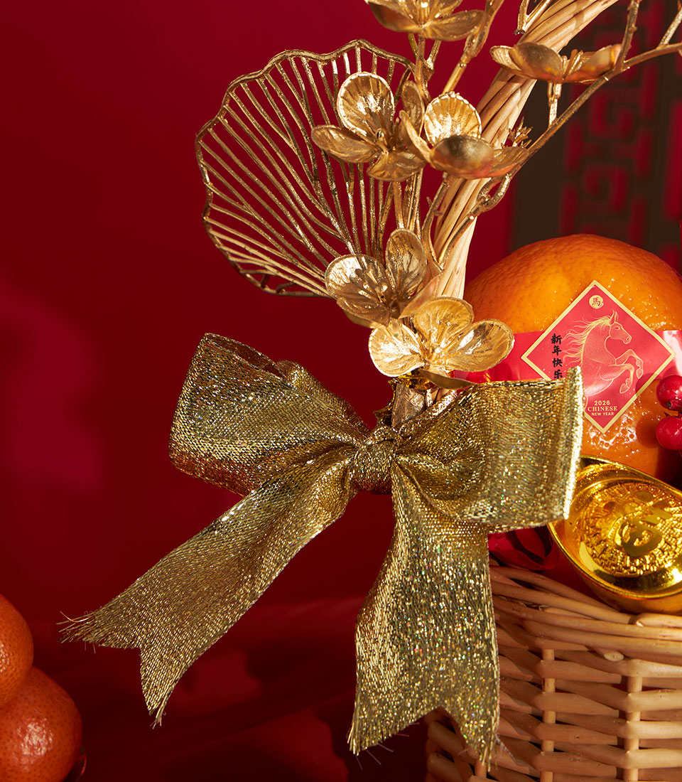 Festive Chinese New Year mandarin orange gift basket with gold bow and floral accents on woven wicker