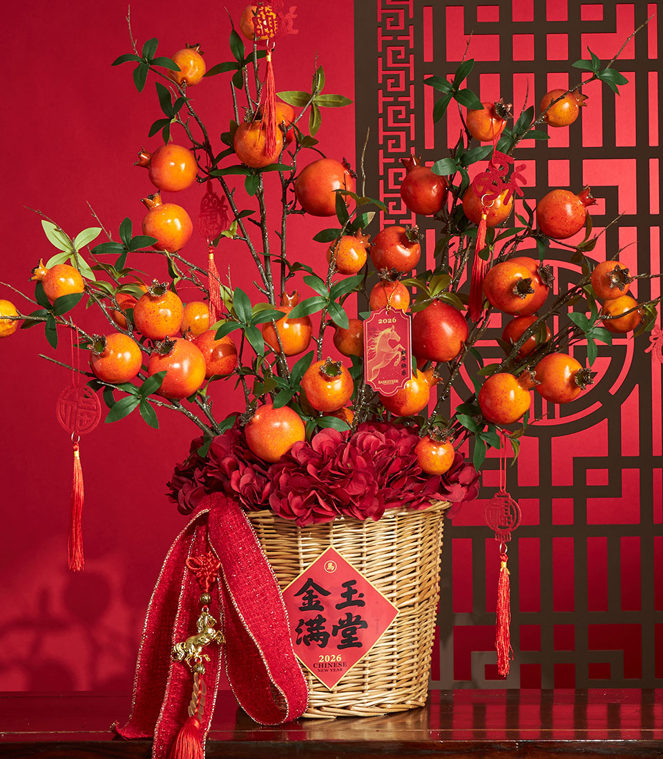 Basketeer premium hamper: festive Chinese New Year gift with bright pomegranates and red hydrangeas in a woven basket with rich red ribbon. Perfect Bangkok delivery.