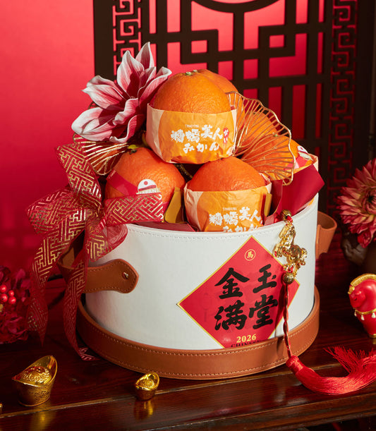 Festive white round gift basket with Ehime oranges, red and gold ribbon, white flower accent, and lucky charms for Chinese