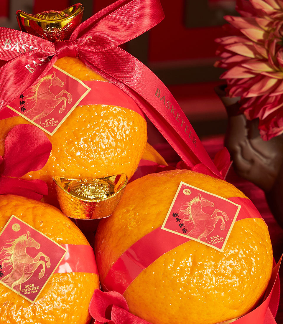 Mandarin oranges with red ribbon and golden horse gift tags, festive Chinese New Year hamper arrangement