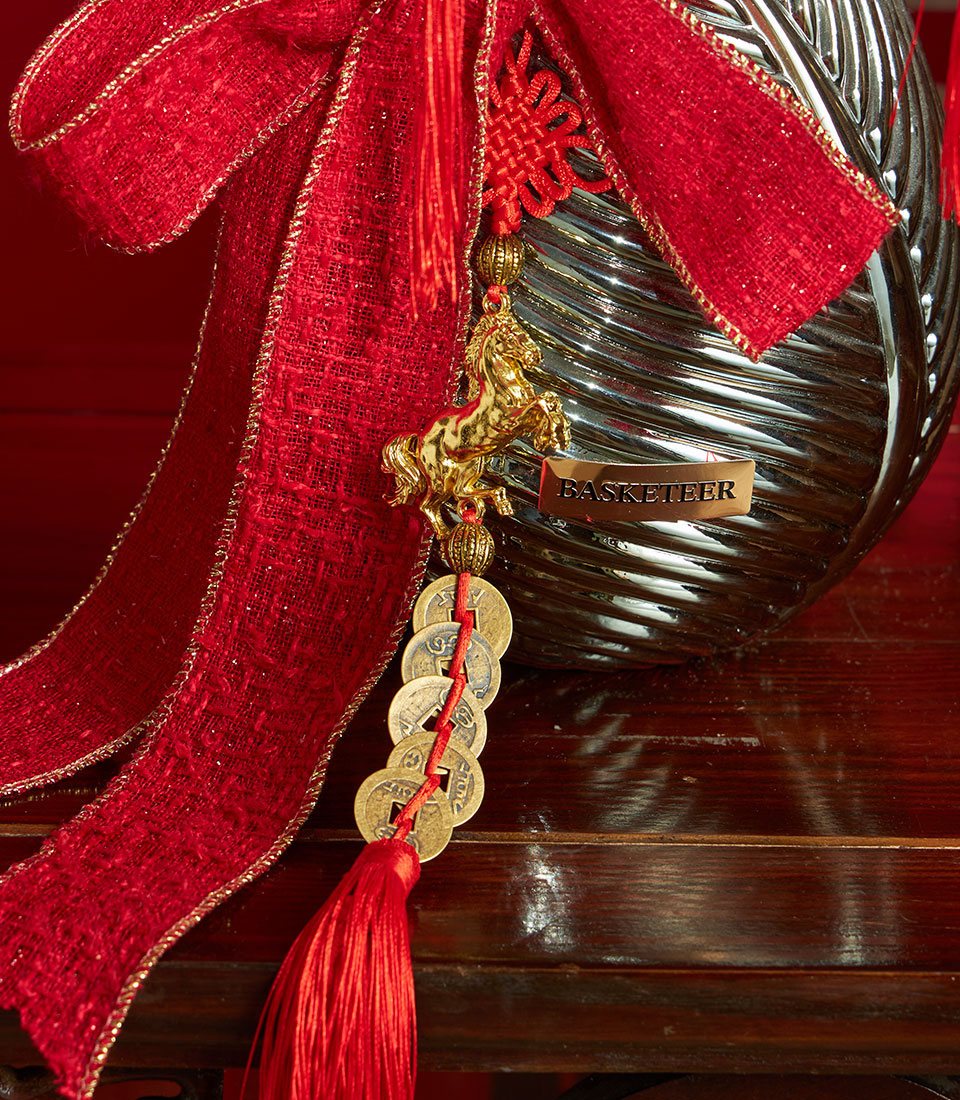 Basketeer luxury gift: a modern silver vase with red ribbon, tassel and gold horse charm for Chinese New Year in Bangkok.