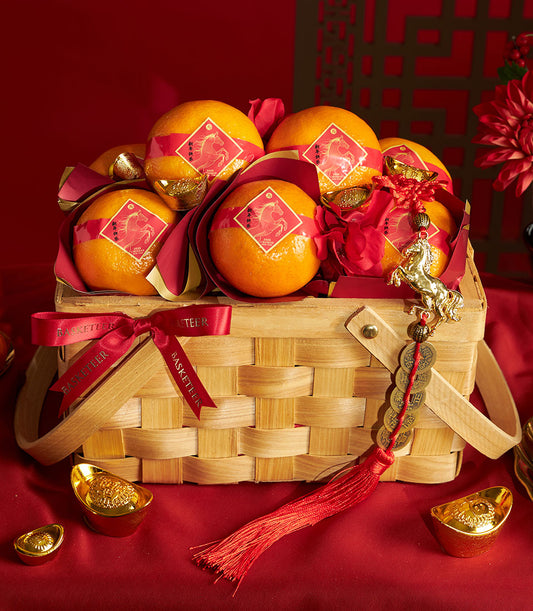 Chinese New Year mandarin orange gift basket with red satin ribbon, gold-wrapped tangerines, and lucky coin tassel
