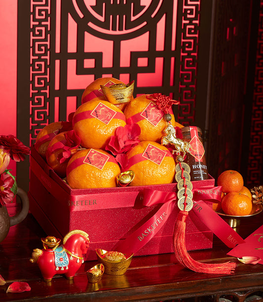 Festive red gift box with mandarin oranges, Charlotte honey, and gold horse charms for Chinese New Year