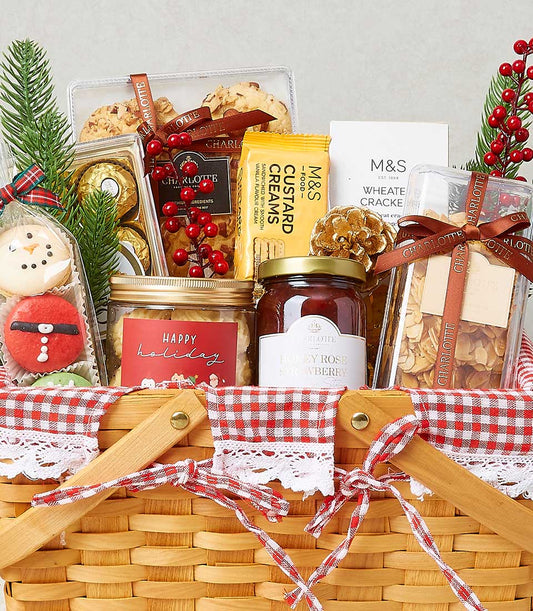 Festive Christmas gourmet snacks hamper with wicker basket, gingham ribbon, cookies, chocolates, and holiday greenery