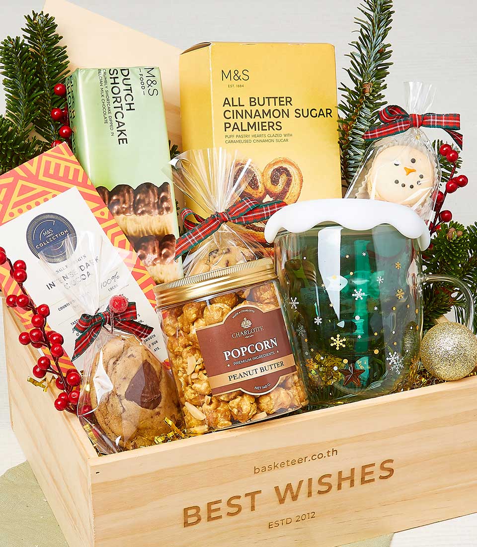 Festive Christmas gift hamper with artisan sweets, snowflake mug, and treats in wooden crate