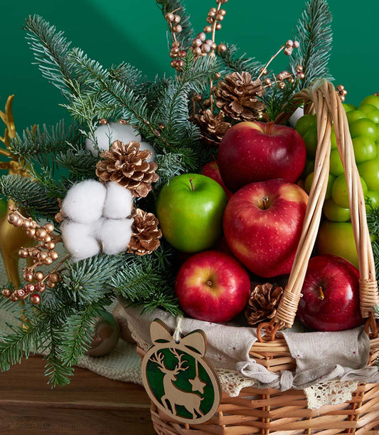 Classic green pine Christmas fruit basket with red apples, grapes, pinecones, and festive ornament