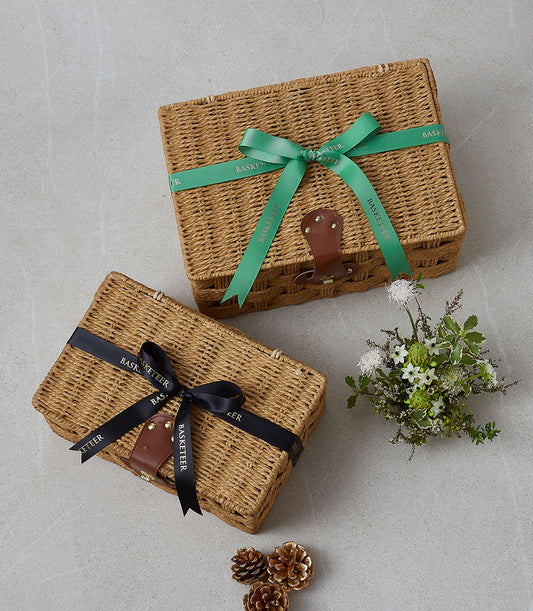 Two Basketeer luxury gift hampers: Wicker baskets with leather closures, ribbon wrap (green and black). Perfect for corporate gifts in Bangkok, premium hamper delivery Thailand.