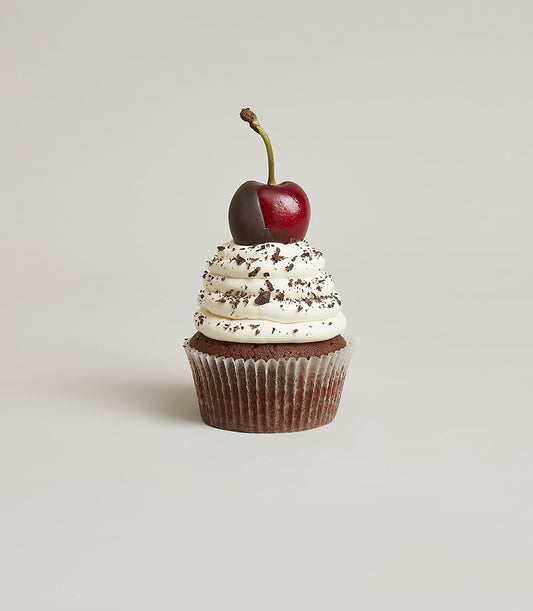 Dark chocolate cupcake with white frosting, chocolate cookie crumbs, and chocolate-dipped cherry