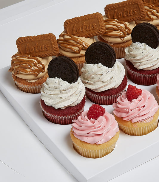 Gourmet cupcake assortment with caramel Lotus, Oreo red velvet, and fresh raspberry flavors in white presentation tray