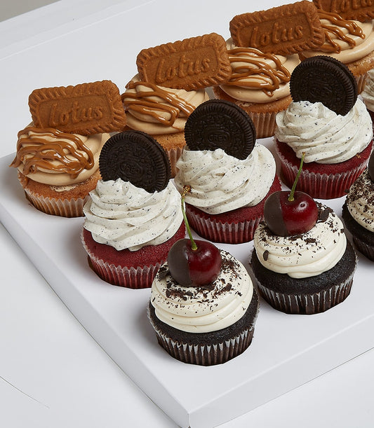 Assorted gourmet cupcakes in white gift tray with Lotus biscuits, Oreo, chocolate, and cherry toppings