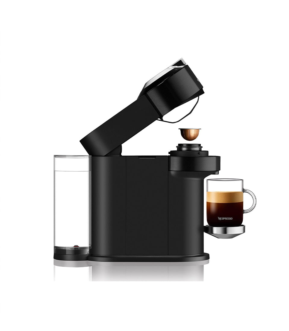 Black Vertuo Next coffee maker with transparent water reservoir and fresh-brewed dark coffee in glass cup