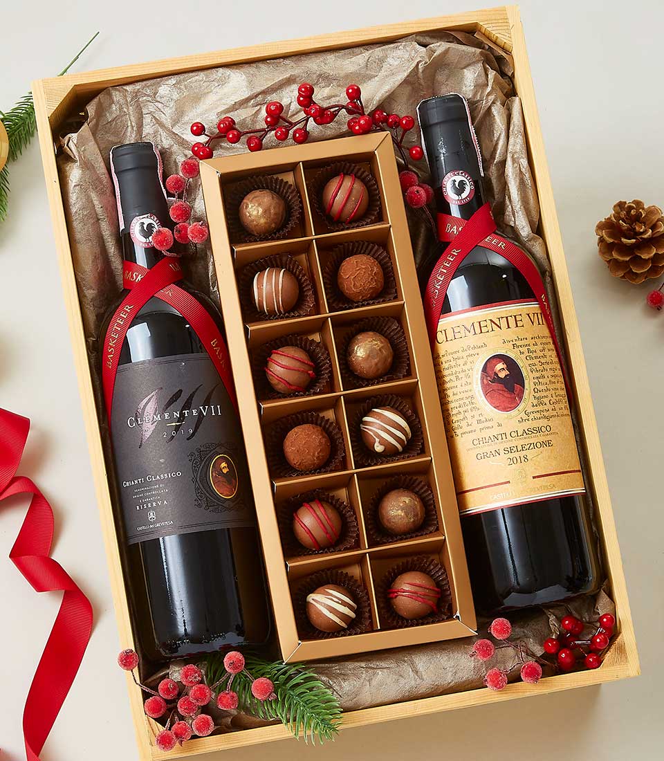 Luxury wine gift box with two Chianti Classico bottles, artisan chocolates, and festive red berry accents in light wood crate