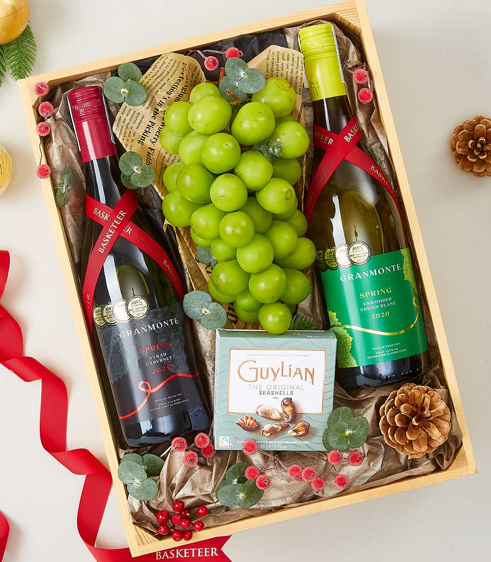 Luxury wine and Guylian chocolate gift hamper with red and white wines, fresh grapes, and seashell chocolates in wooden crate