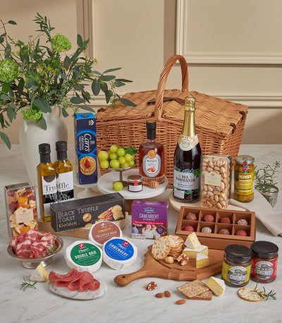 Luxury wicker picnic hamper with gourmet cheeses, truffle oil, crackers, cured meats, and artisan chocolates