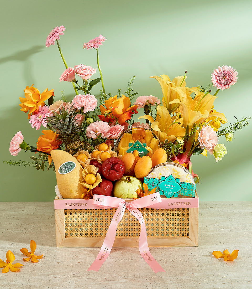 Exotic Thai fruit gift basket with mango, guava, rose apples, and fresh flowers in woven wooden crate