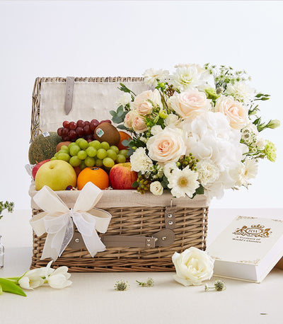 Woven wicker fruit and flower gift basket with fresh roses, hydrangeas, grapes, cantaloupe, and seasonal fruit
