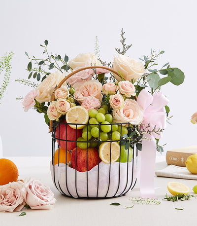 Fresh fruit basket with pink roses, apples, oranges, and grapes for birthday celebrations