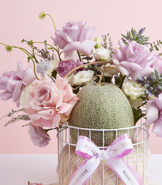 Fresh cantaloupe with premium roses and mixed flowers in white wire gift basket