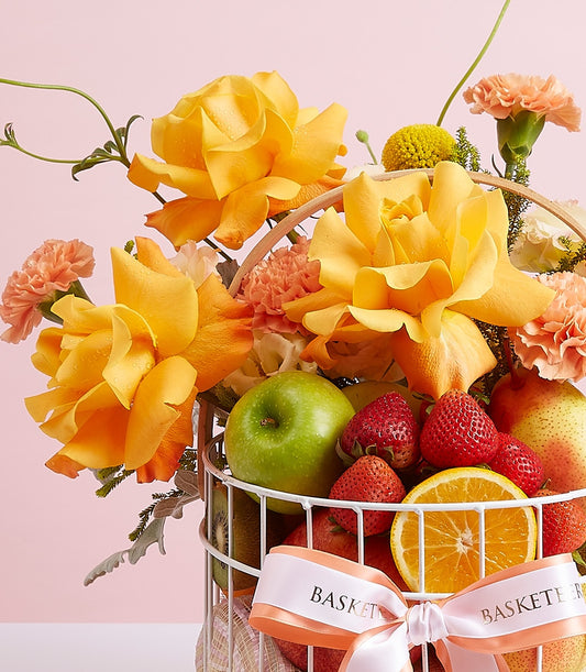 Fresh fruit and flower gift basket with strawberries, apple, pear, yellow roses, and peach carnations