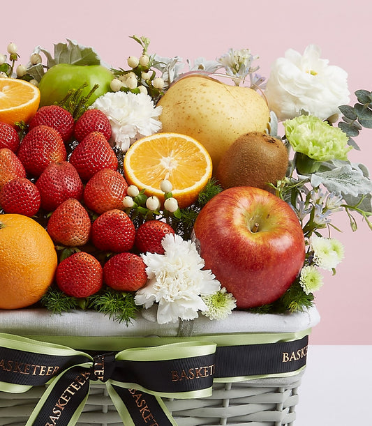 Premium mixed fruit and flower basket with strawberries, apples, pears, and white blooms in woven grey base with black ribbon