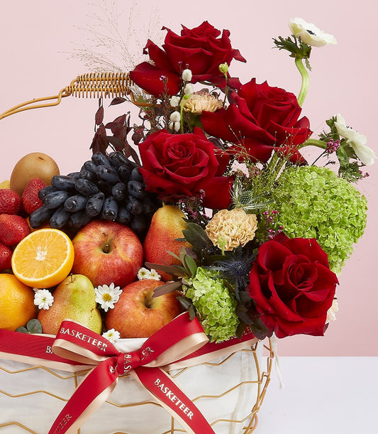 Luxury fruit and flower gift basket with red roses, fresh seasonal produce, and red satin ribbon